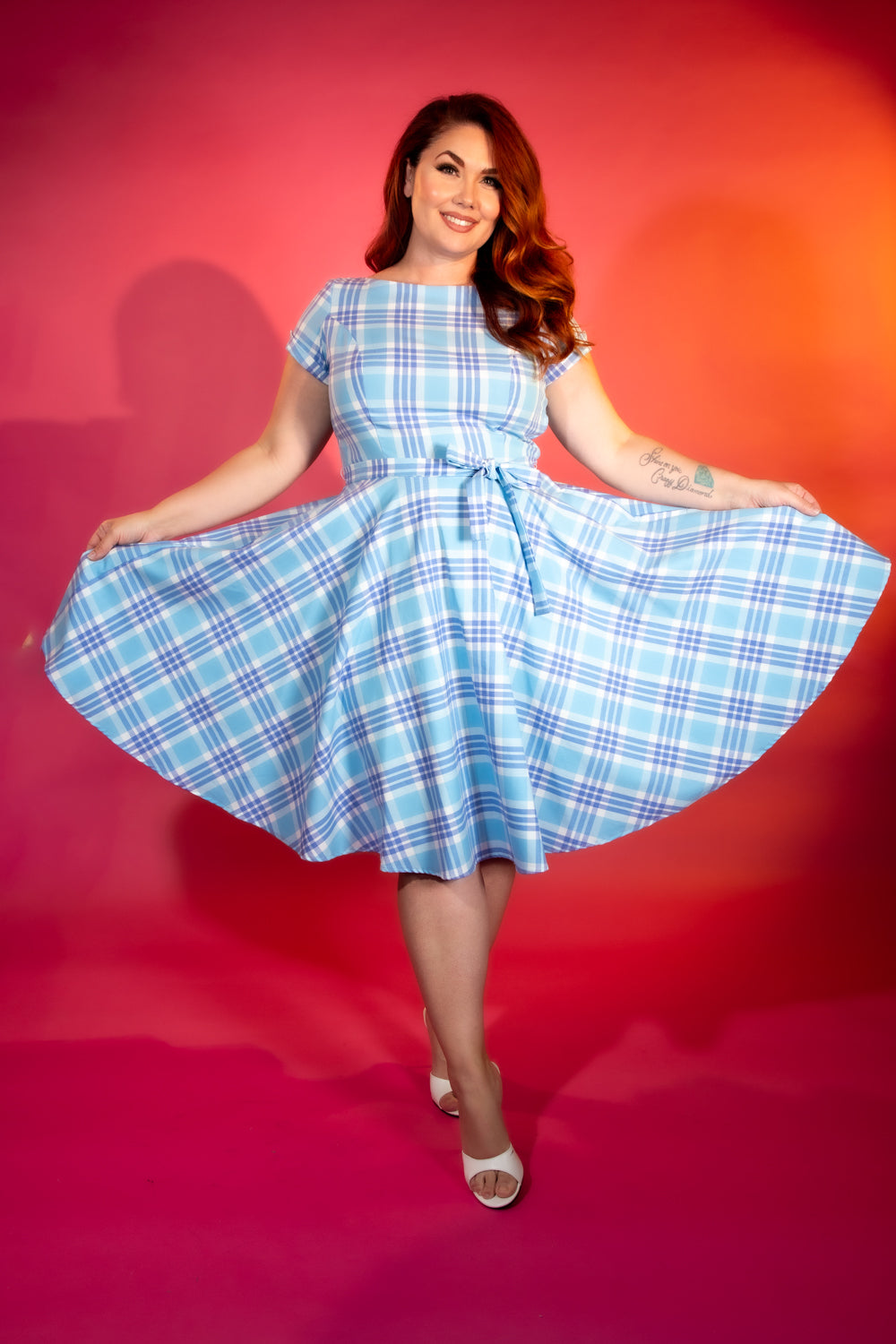 Woman wearing a blue plaid dress against a red background