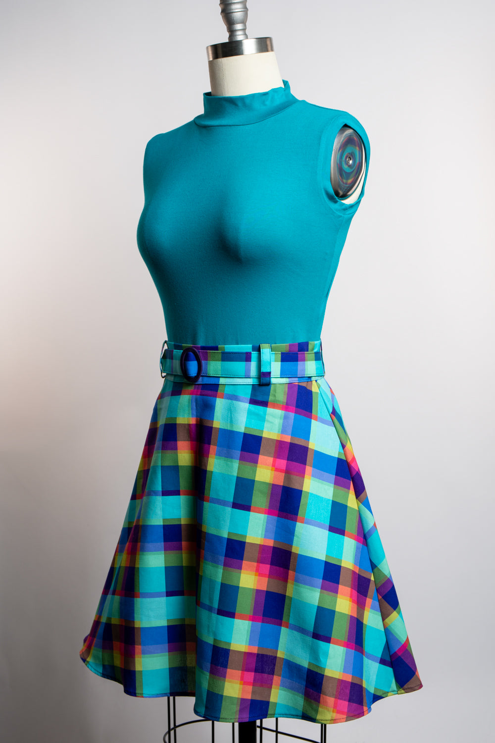 Teal top and plaid skirt on a mannequin against a plain background