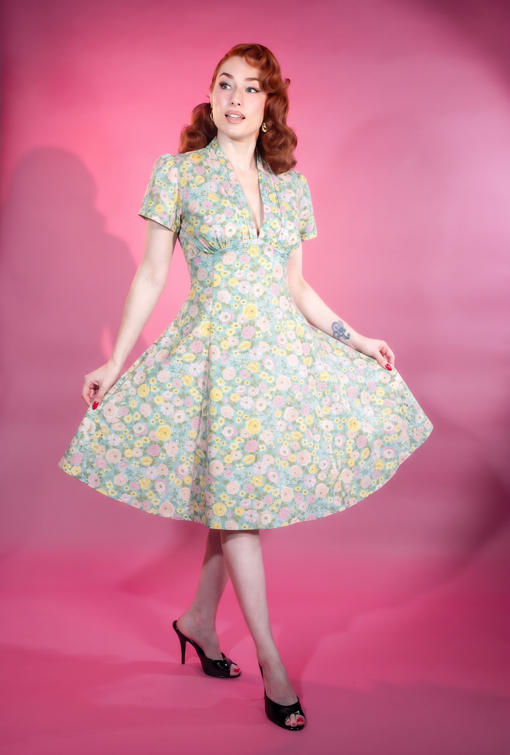Woman wearing a floral dress against a pink background vintage retro pinup 1950s 1960s style midi dress